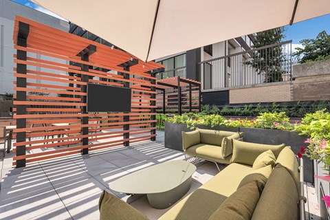A patio with a white table and chairs and a TV on a stand.