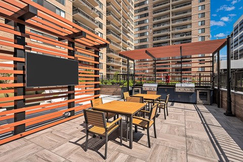 A patio with a table and chairs and a TV on a wall.