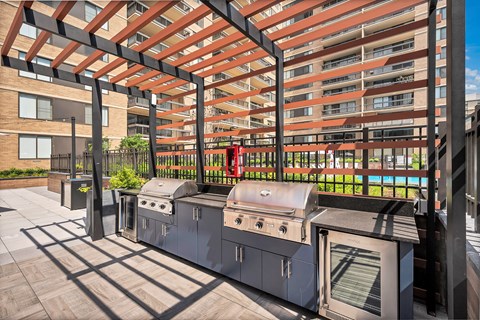 A BBQ grill is on a patio with a building in the background.