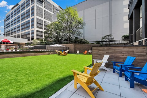 A yellow chair is in the foreground of a patio with blue chairs and a table.