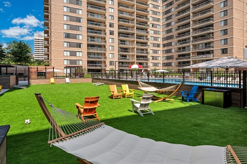 A playground area with a slide, swings, and seating area in front of a large apartment building.