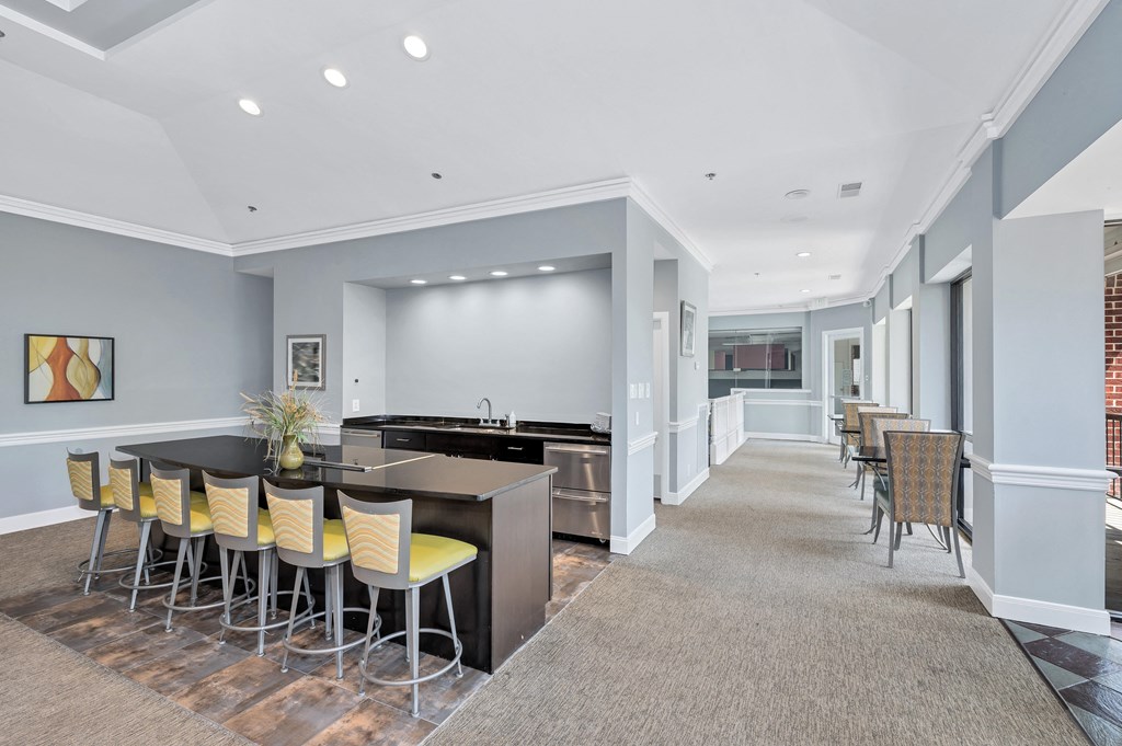 a common area with a bar and chairs at the enclave at woodbridge apartments in sugar land