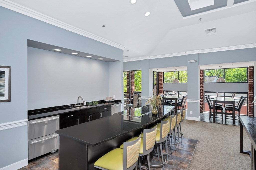 a kitchen with a long black counter and yellow chairs