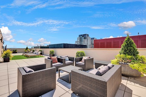 A patio with grey furniture and a tree in a planter.