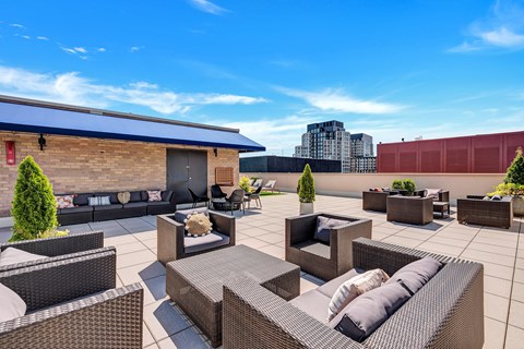 A patio with black wicker furniture and a red building in the background.