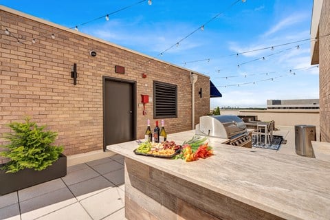A balcony with a table set for a meal and string lights above.