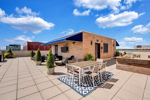 A patio with a table and chairs is surrounded by potted plants.