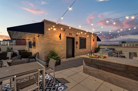 A patio with a table and chairs is lit up with string lights.