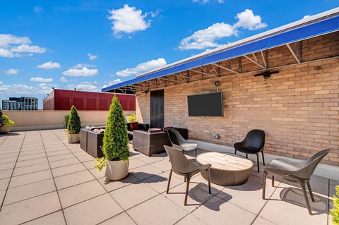 A patio with a table, chairs, and a TV mounted on a brick wall.