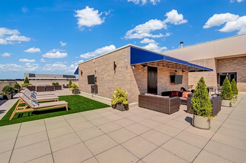 A modern building with a patio and a blue sky in the background.