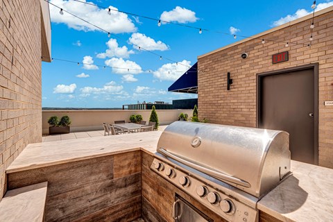 A silver outdoor grill is on a patio with a view of the ocean.