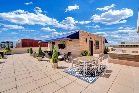 A patio with a table and chairs is surrounded by potted plants.