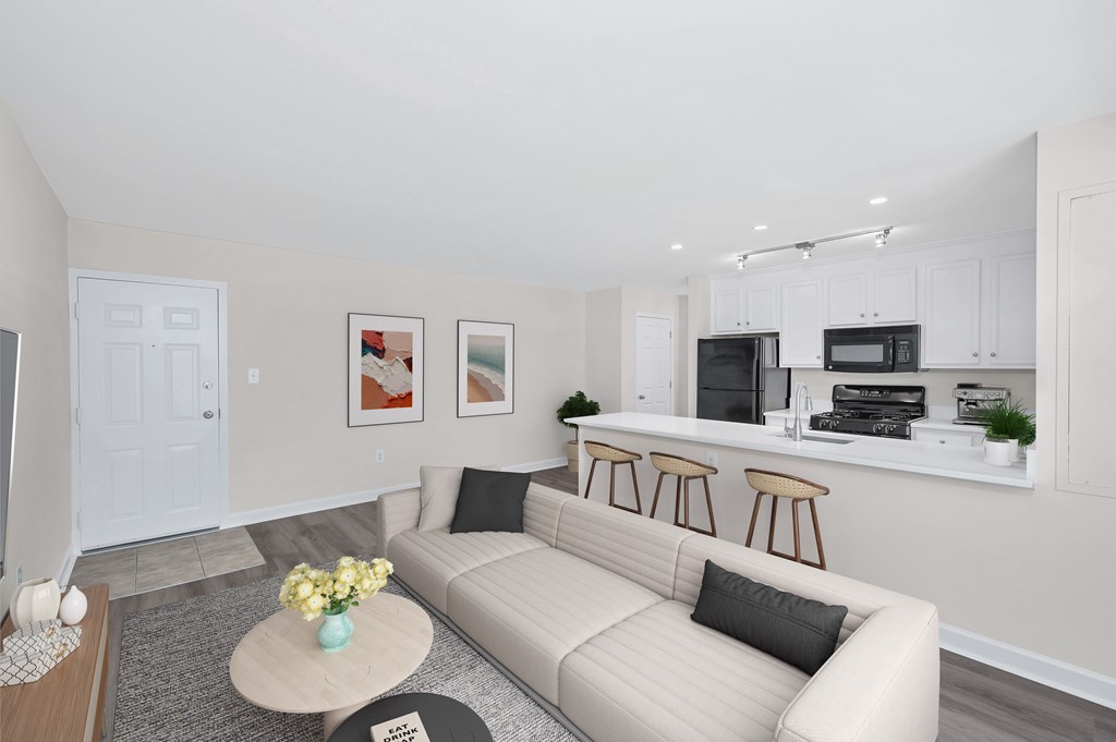 A living room with a couch, coffee table, and kitchen area in the background.
