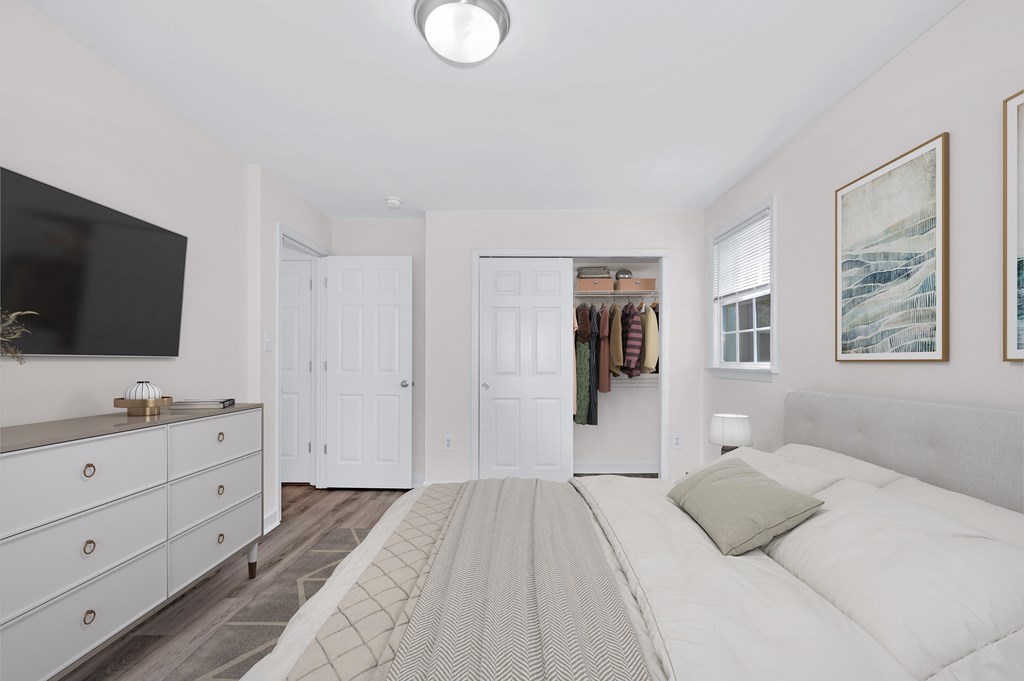 A bedroom with a large bed and a television on the wall.