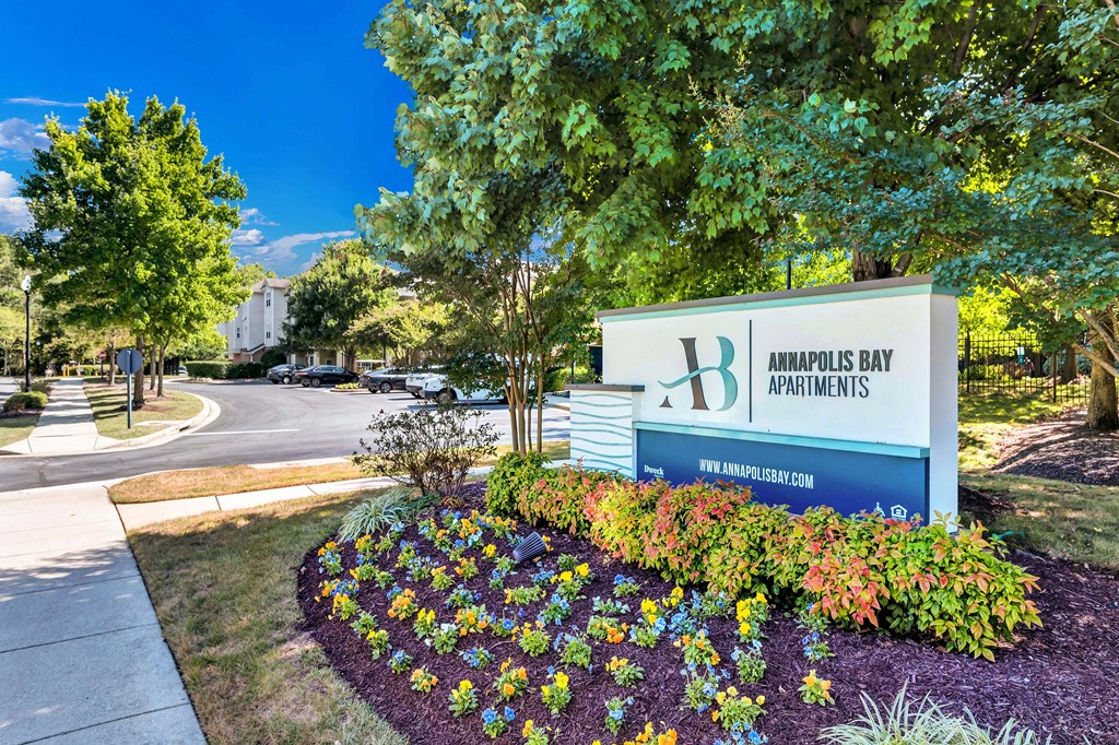 a sign for the headquarters of amours bay properties in front of trees and flowers
