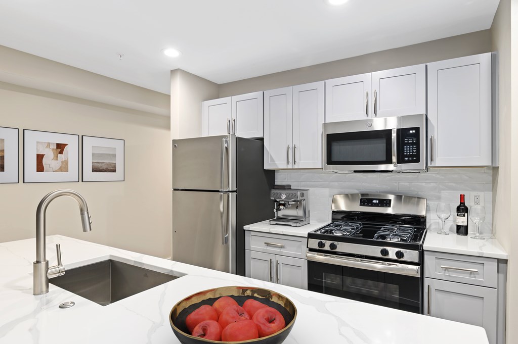 A kitchen with a bowl of tomatoes on the counter.