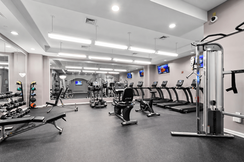 A spacious gym with various exercise equipment and mirrors on the wall.