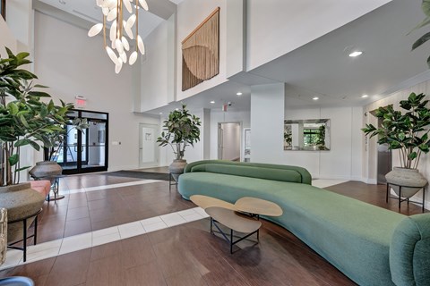 A modern living room with a long green couch and a wooden beam on the wall.