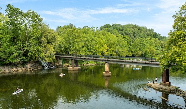 a bridge over a river with people kayaking on it