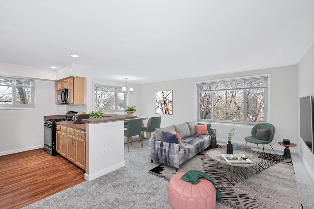 a living room with a couch a table and a chair and a kitchen with a stove and