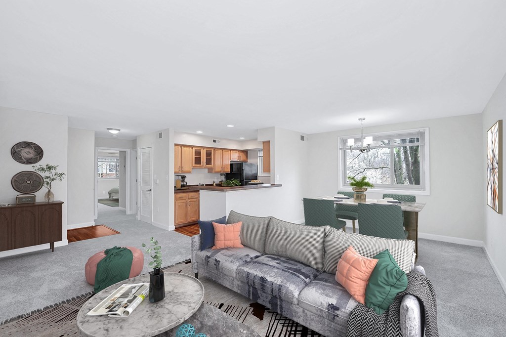 a living area with a couch coffee table and a kitchen in the background