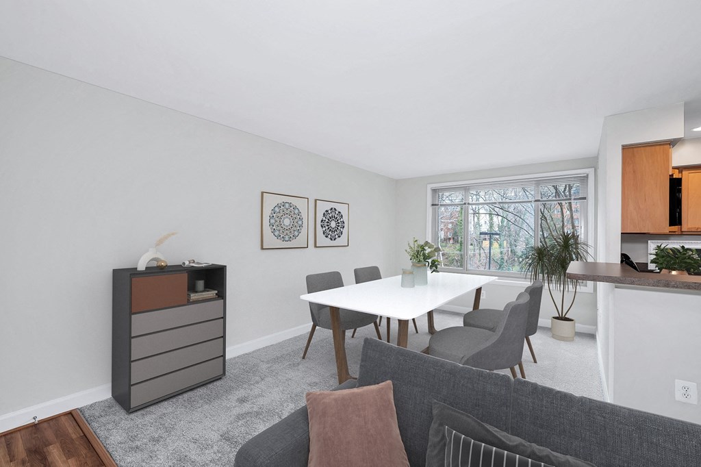 a dining area with a table and chairs and a kitchen in the background