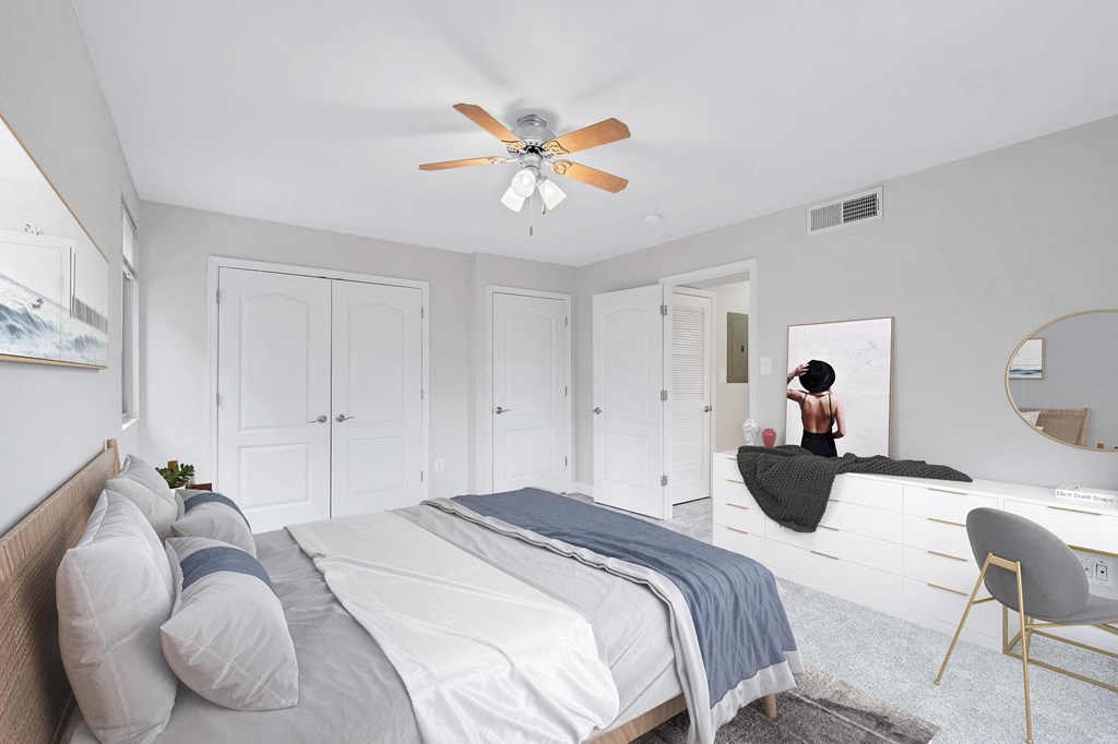 a bedroom with white walls and a white bed with gray pillows
