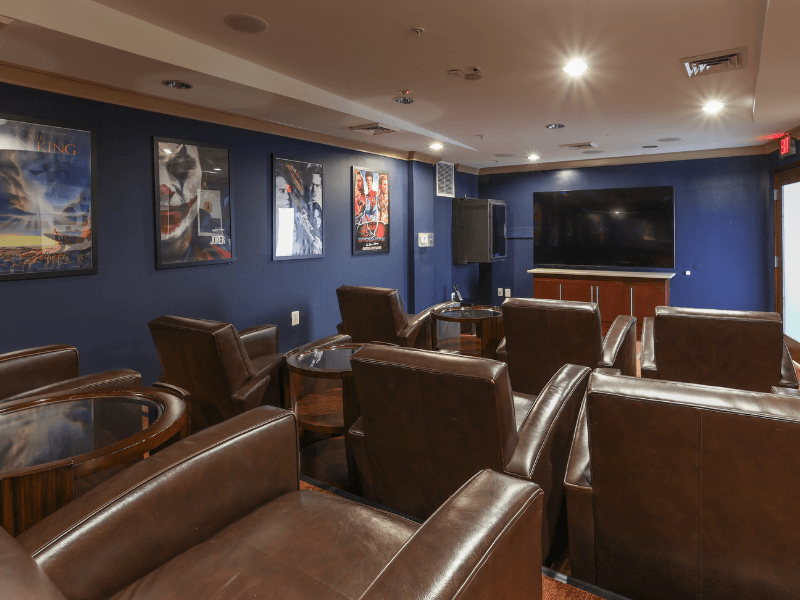 a cinema room with leather chairs and a flat screen tv