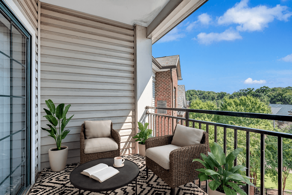 A balcony with a table, two chairs, and a potted plant.