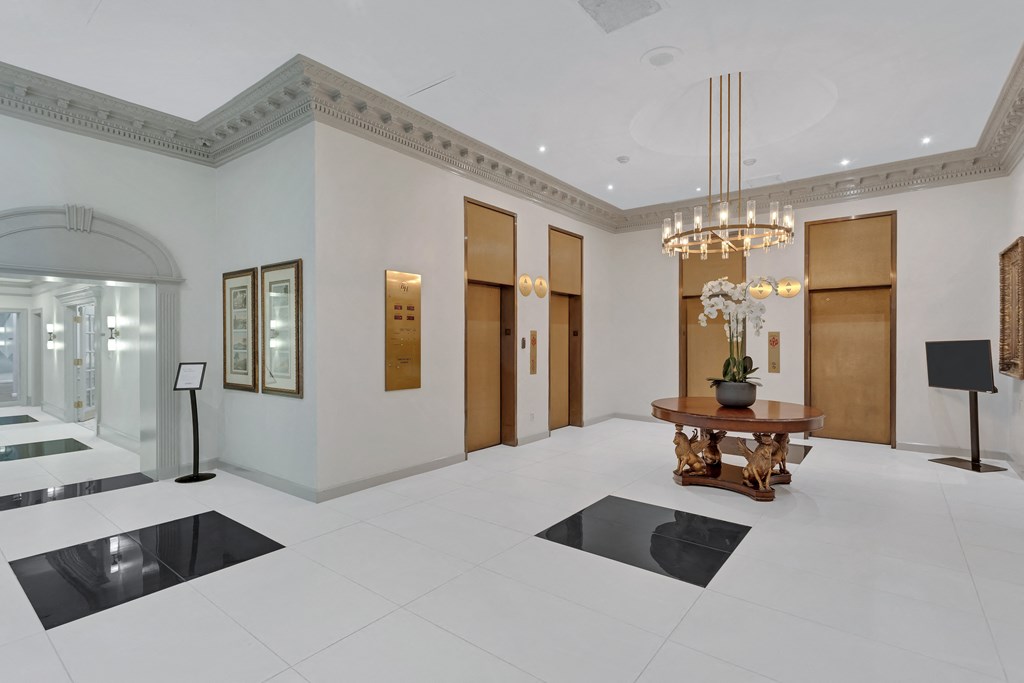 a lobby with a table and three elevators and a chandelier