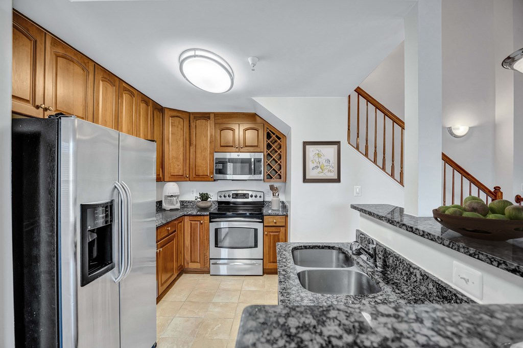 A kitchen with a refrigerator, sink, and stove.