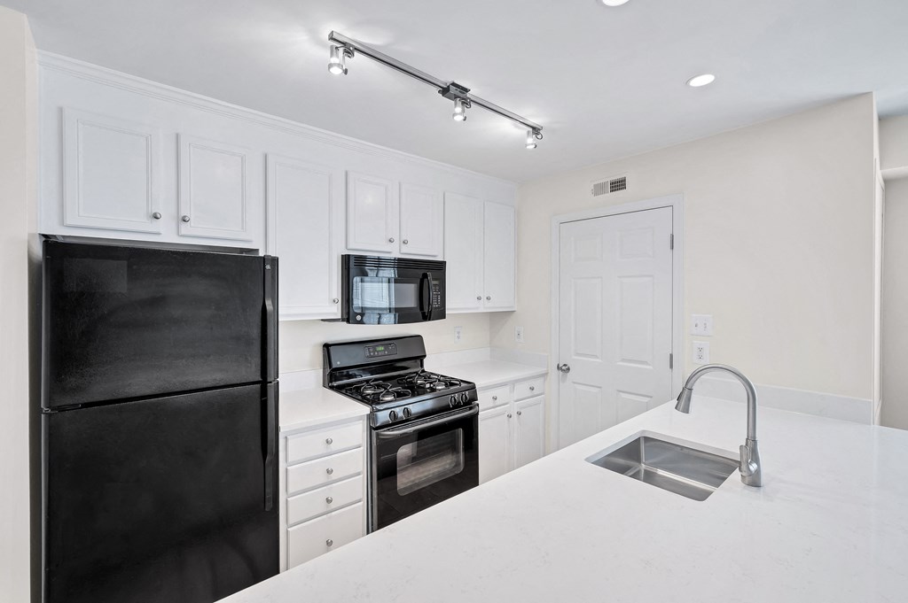 a kitchen with white cabinets and black appliances