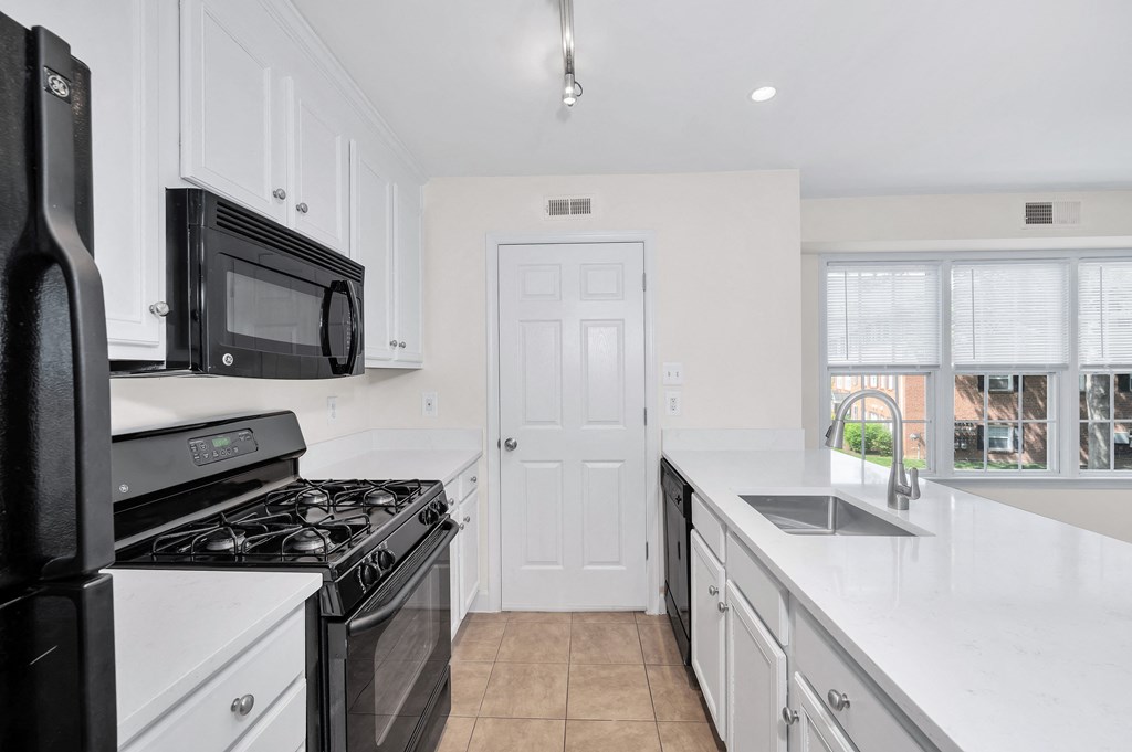 a kitchen with white cabinets and black appliances