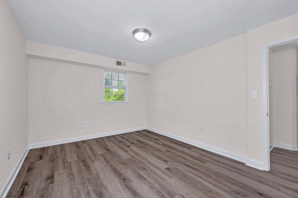 a bedroom with hardwood floors and white walls