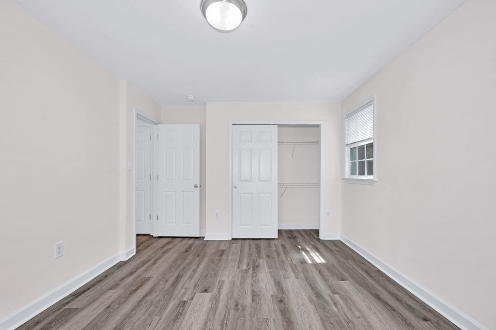 a bedroom with hardwood floors and white walls