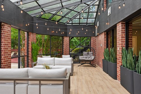 A patio with a white couch and a glass roof.
