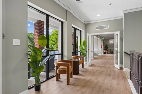 A long hallway with a table and chairs on the left and a doorway on the right.