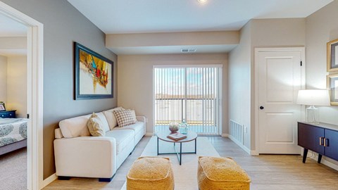 A living room with a white couch, a yellow ottoman, and a painting on the wall.