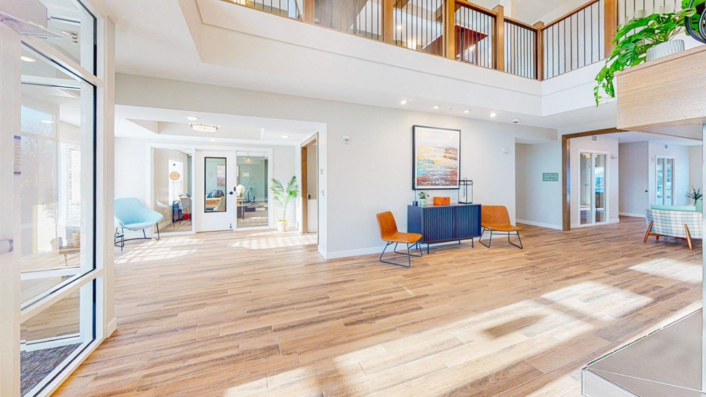 A spacious living room with wooden floors and a staircase leading to the upper level.