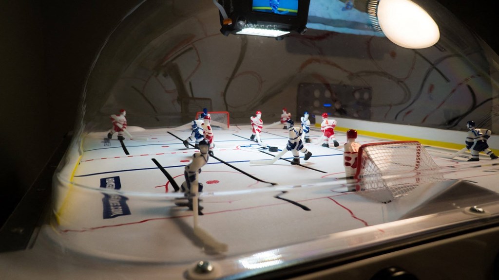 A group of small plastic people are playing a game of hockey on a table.