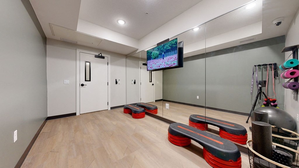 A room with a wooden floor and a television mounted on the wall.