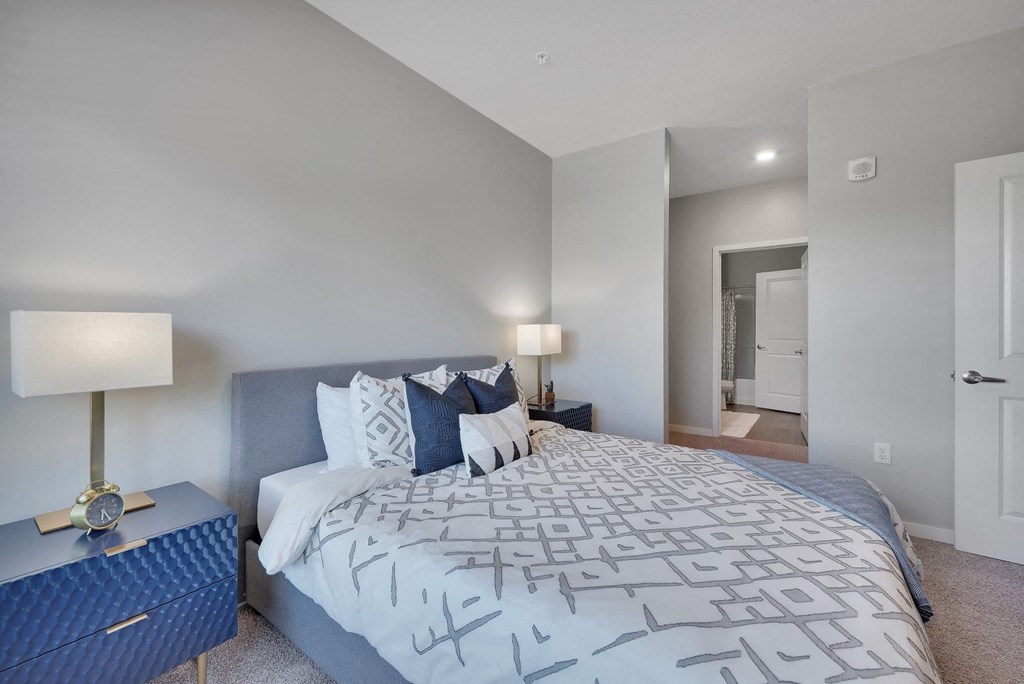 A bedroom with a large bed and a nightstand with a lamp.