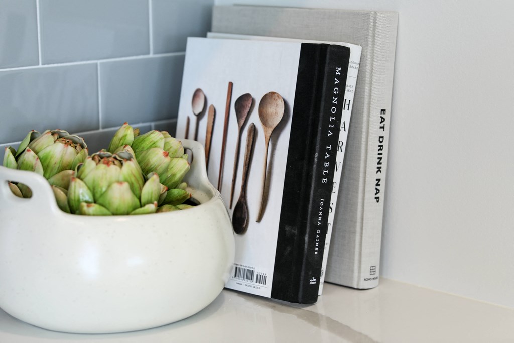 a close up of a white vase with a green plant in it next to a book