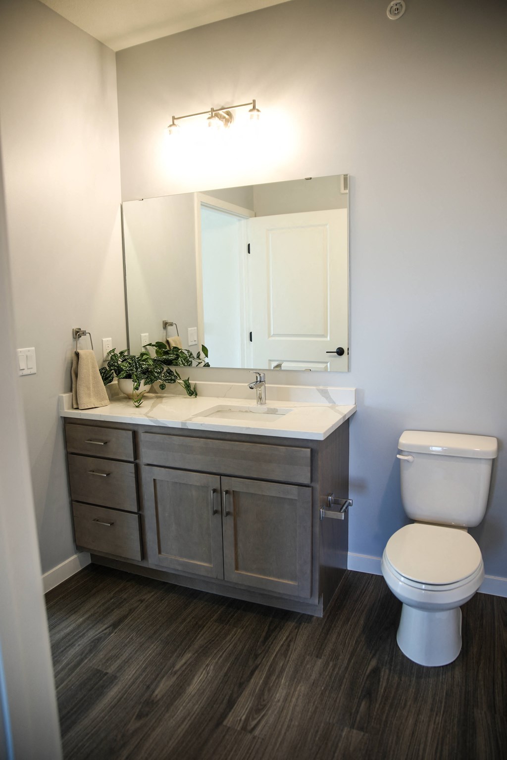 a bathroom with gray cabinets and a white toilet