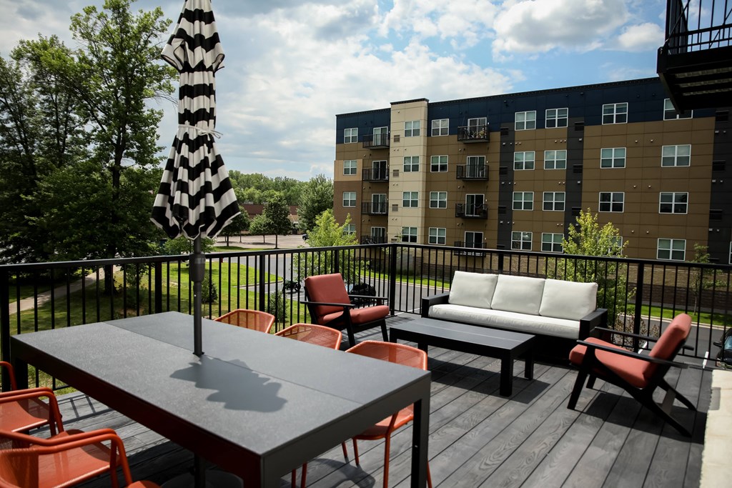 a patio with a table and chairs and a couch on a balcony in front of an apartment