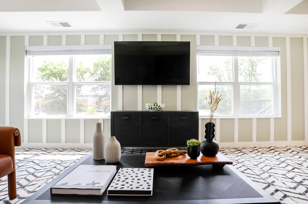 a living room with a black coffee table and a tv on the wall