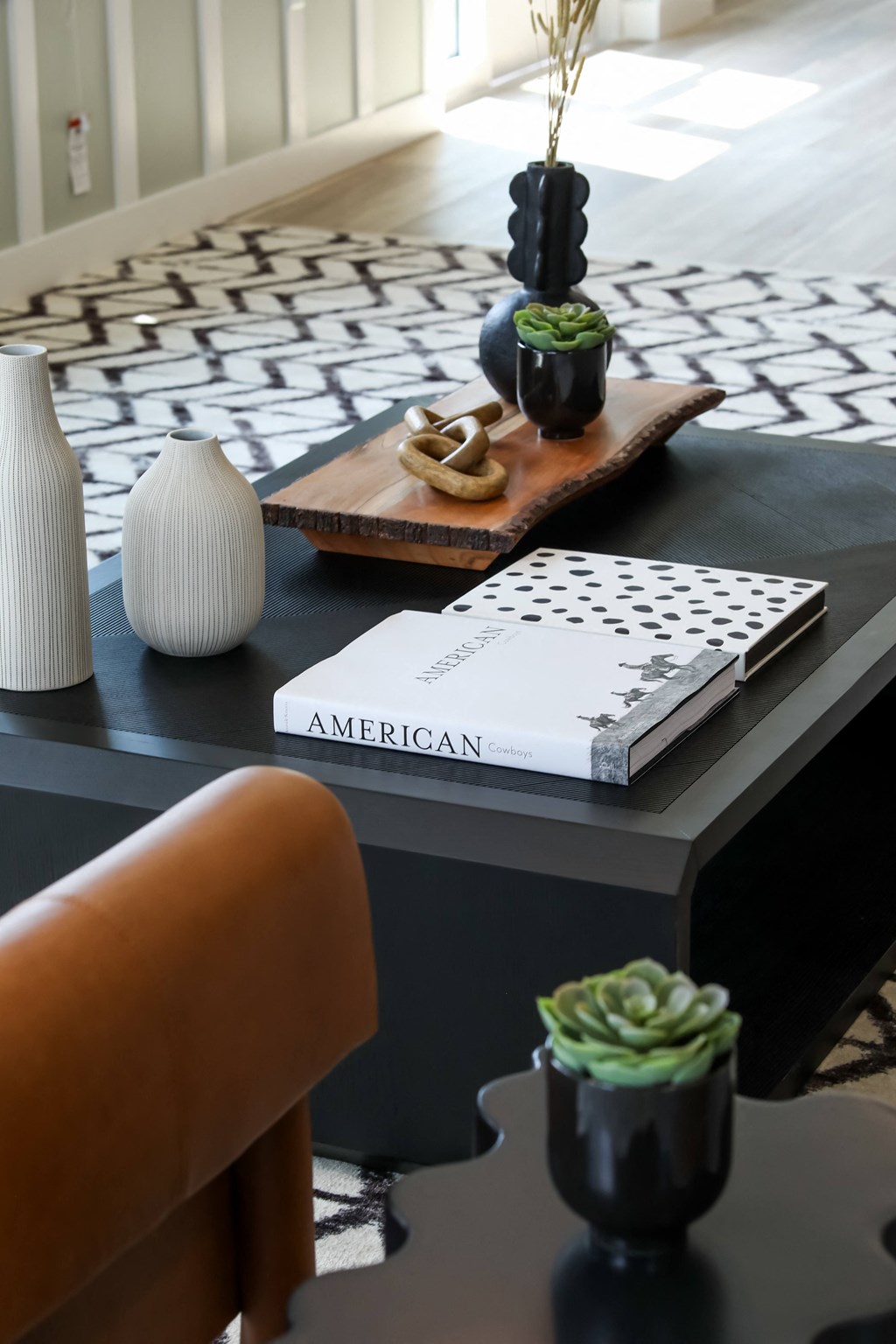 a black coffee table with a black and white geometric rug on top