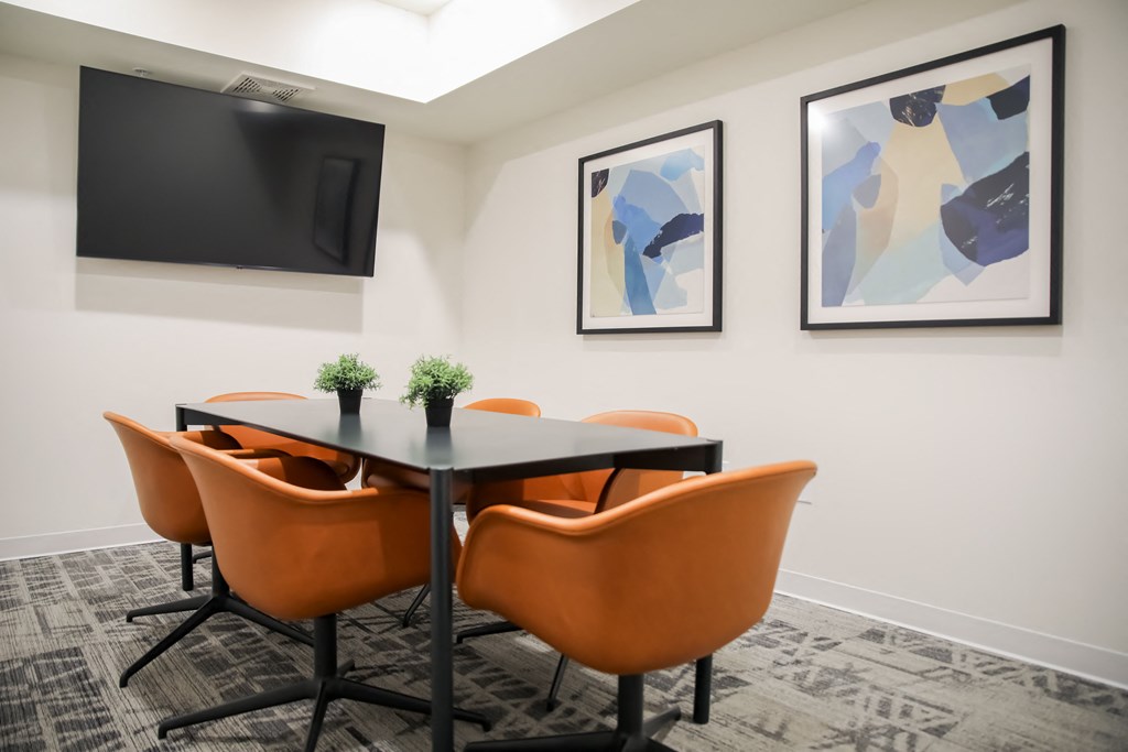 a meeting room with a table and chairs and a tv on the wall