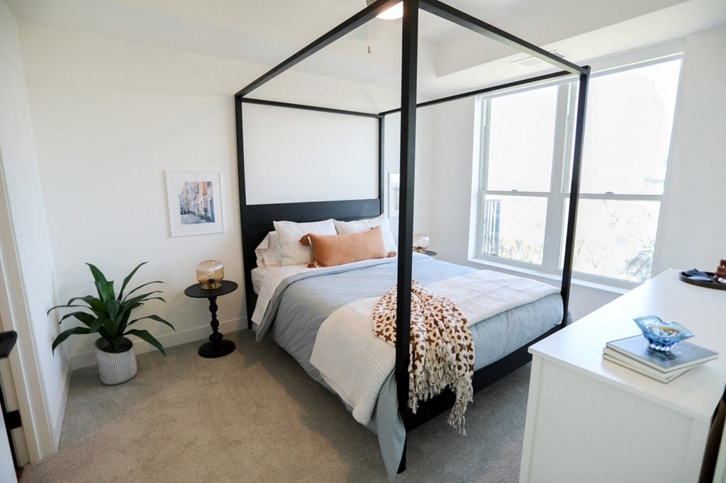a bedroom with a four poster bed and a large window