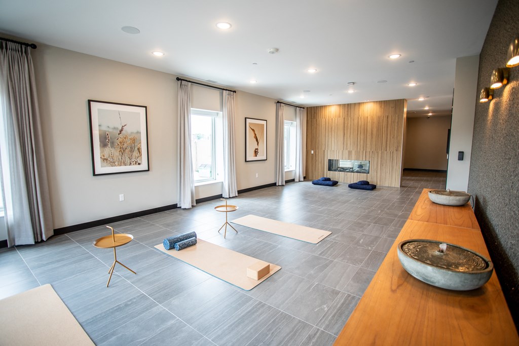 a large room with yoga mats on the floor and a fireplace